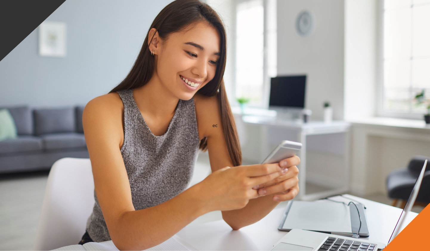 woman working from home seated at a table using a laptop and mobile phone with an app to reduce stress