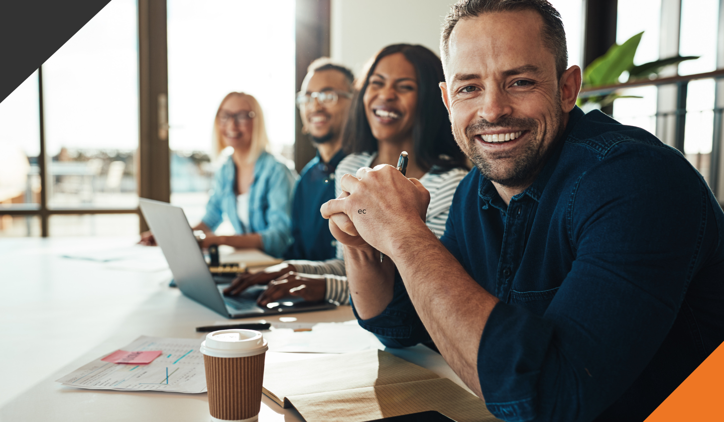employees seated at a table smiling after learning the top 3 tips to reduce employee stress at work