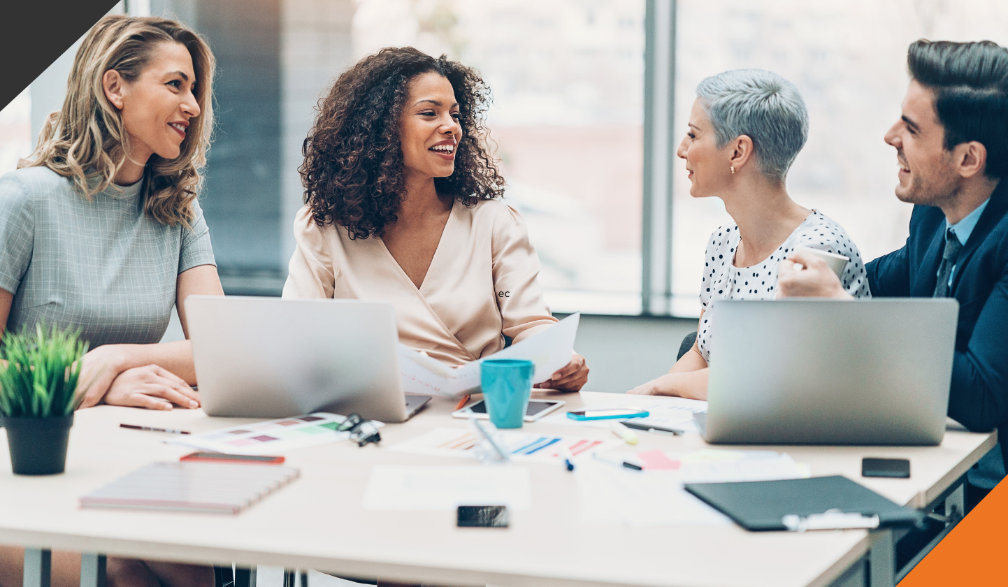 4 employees seated around a table discussing New Years Resolutions All Leaders Should Consider