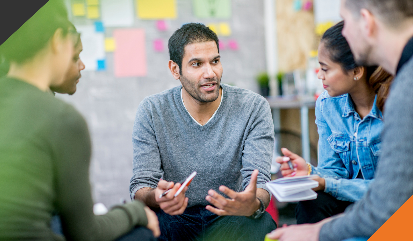 5 people seated in a circle in an office setting discussing