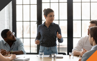 a training and development coach leads a development session for four employees in a corporate office meeting room