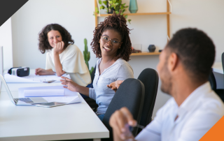 three employees seated in a row at a desk in an office