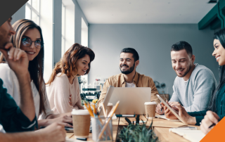 five employees in a meeting room at a desk executing successful training and development strategies